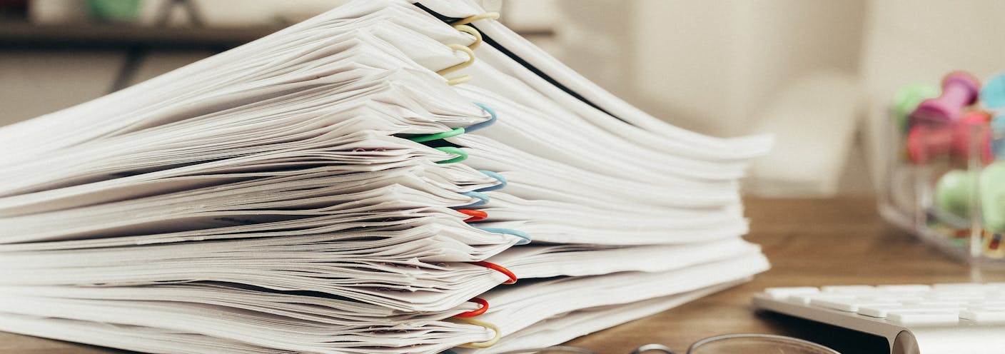 Stacks of clipped vendor proposals and contracts ready to upload